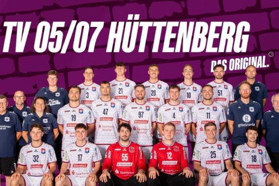 Gruppenfoto der Handballmannschaft und des Stabs von TV 05/07 Hüttenberg in weißen und roten Trikots, posierend vor einem violetten Hintergrund mit dem Mannschaftsnamen und den Logos für die Saison 2026/27 der 2. Handball-Bundesliga.