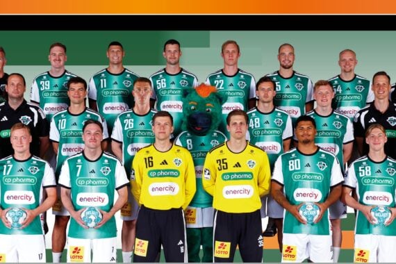 Eine Herren-Handballmannschaft posiert in grünen Trikots, wobei zwei Torhüter in gelben Trikots vorne in der Mitte stehen. Ein Maskottchen in einem Bärenkostüm steht in der Mitte. Trainer und Betreuer stehen an den Seiten.