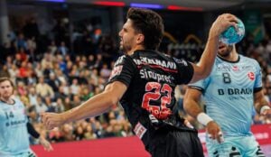 Ein Handballspieler in einem schwarzen Trikot macht sich während eines Spiels bereit, den Ball zu werfen.