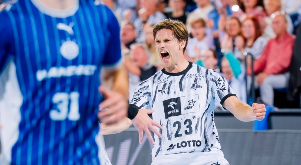 HANDBALL 2026/27: THW Kiel - VfL Gummersbach Ein Handballspieler im weißen Trikot mit der Nummer 23 jubelt begeistert auf dem Spielfeld. Im Vordergrund ist ein weiterer Spieler im blauen Trikot mit der Nummer 31 zu sehen. Im Hintergrund ist das Publikum zu sehen, das jubelt.