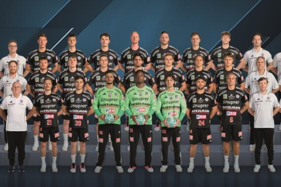 Mannschaftsfoto der Handballspieler und Betreuer des HC Erlangen in schwarzen und limettengrünen Trikots.