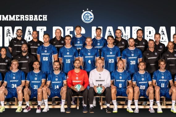 Mannschaftsfoto des Handballvereins VfL Gummersbach, auf dem Spieler und Trainer in blauen Trikots in Reihen sitzend und stehend zu sehen sind; hinter ihnen ist in großen Buchstaben „HEIMAT DES HANDBALLS“ zu lesen.